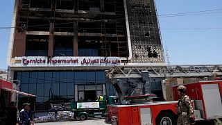 Feuerwehrleute versammeln sich vor einem brennenden Supermarkt in Kut, Irak.