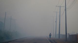  A person walks on the BR-319 highway through smoke from a forest fire that reaches Careiro Castanho in Brazil's Amazonas state in 2023.