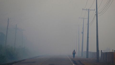  A person walks on the BR-319 highway through smoke from a forest fire that reaches Careiro Castanho in Brazil's Amazonas state in 2023.